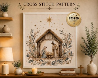 May include: A framed cross stitch pattern featuring a nativity scene with a wooden stable, figures of Mary, Joseph, and the infant Jesus, surrounded by a floral wreath and a star. The text CROSS STITCH PATTERN and a gold TESTED PATTERN seal are visible.