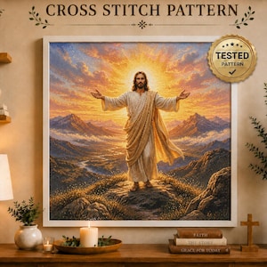 May include: A cross stitch pattern featuring a central figure with arms outstretched standing on a mountain peak at sunrise. The scene includes a golden sky, distant mountains, and a river valley. A gold seal reads TESTED PATTERN.
