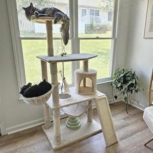 May include: A white ceramic mug with a black handle and the text "But First, Coffee" in a bold, black font. The mug is set against a blurred background, suggesting a cozy setting.