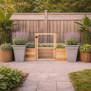 May include: A backyard garden scene featuring a wooden fence, a small wooden gate, and raised garden beds. The scene includes potted plants in gray and woven baskets, with a gravel pathway and stone pavers.