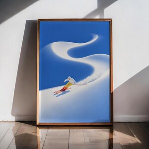 Könnte beinhalten: Ein gerahmter vertikaler Wandkunstdruck, der einen Skifahrer in weißer Jacke und gelber Hose zeigt, wie er einen Pfad einen hellweißen, schneebedeckten Hang hinunterzieht, vor einem tiefblauen Himmel. Der Skifahrer hält rote Stöcke und trägt rote Skier, wodurch eine lange, geschwungene Spur im Schnee hinter ihm entsteht. Das Kunstwerk ist in einem einfachen Holzrahmen gefasst.