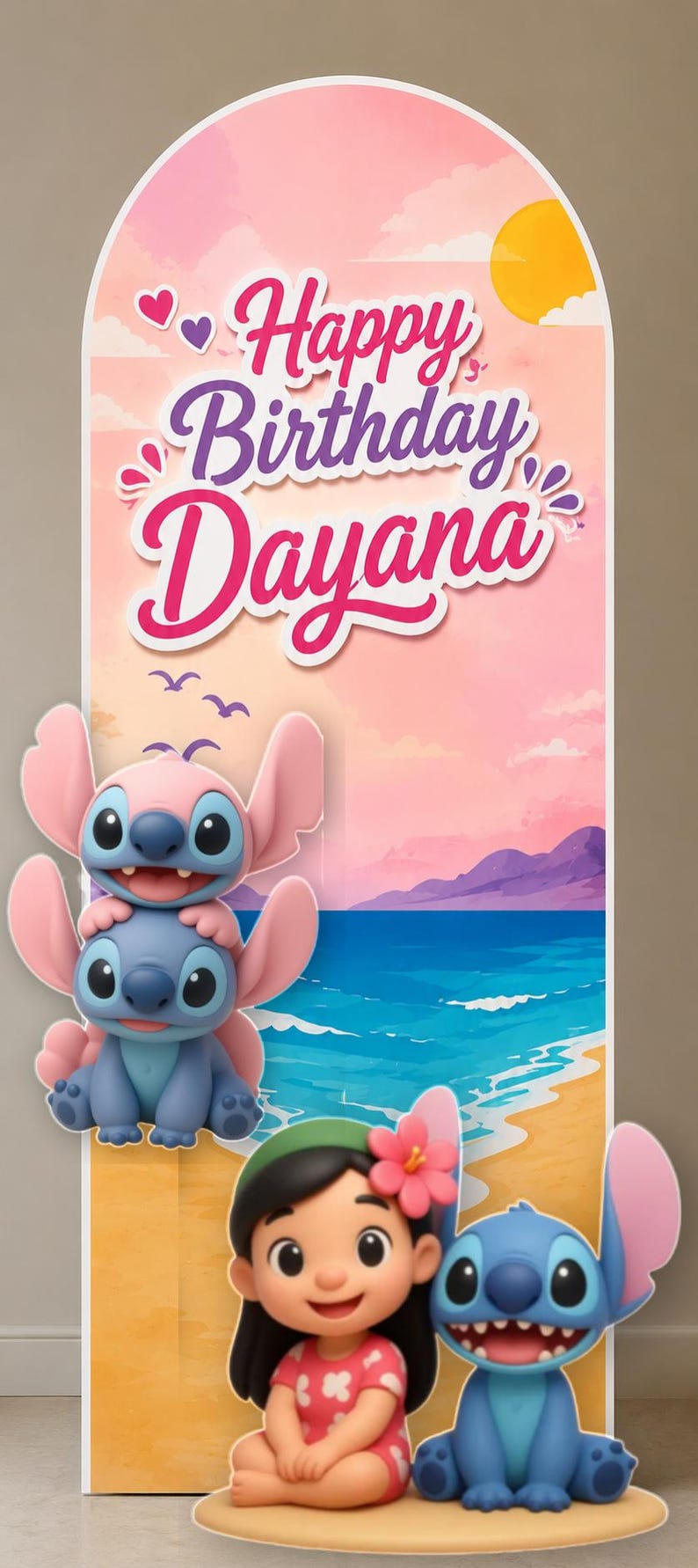 May include: An arched backdrop display featuring a beach sunset scene with the text Happy Birthday Dayana. The design includes a stacked pink and blue alien character, a girl with a pink flower in her hair, and a blue alien character at the base.