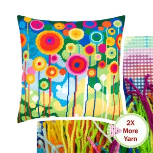 Peut inclure: Une housse de coussin carrée en canevas présentant un motif floral abstrait et vibrant avec des formes circulaires dans des tons de rose, orange, jaune, vert et bleu. Une section montre une toile à grille avec des fils colorés et le texte 2X More Yarn.