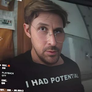 Puede incluir: Una camiseta negra de cuello redondo con el texto "I HAD POTENTIAL" en blanco. La persona de la imagen lleva gafas con montura dorada. El fondo incluye una pantalla con texto y un panel de control.