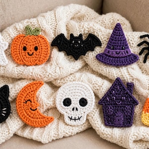 May include: A collection of crocheted Halloween-themed appliques including an orange pumpkin, a black bat, a purple witch hat, an orange crescent moon, a white skull, and a purple house, all featuring embroidered facial details.