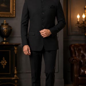 Può includere: Un abito bandhgala nero a tinta unita composto da una giacca con colletto alla coreana, cinque bottoni frontali, maniche lunghe e un taschino sul petto con pochette nera abbinata. Il completo include pantaloni neri sartoriali e scarpe eleganti.