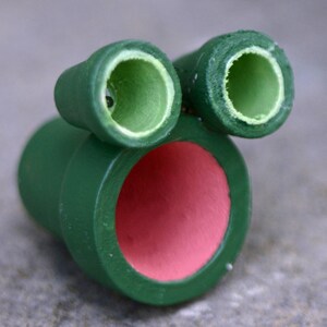 May include: Green ceramic planter with a large, round opening and two smaller, round openings on the top. The planter is made of a smooth, green ceramic and has a glossy finish.