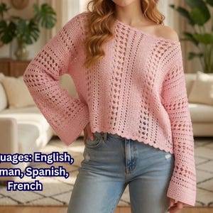 May include: A light pink, open-weave crochet sweater with long sleeves and a boat neck. The sweater has a scalloped hemline and is paired with blue jeans. The image also contains text that says "Languages: English, German, Spanish, French."