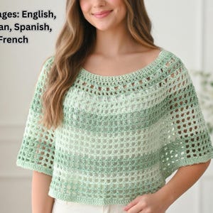 May include: A light green and white crochet top with short sleeves. The top has a scoop neckline and a striped pattern. The open weave design is visible throughout the garment. The top is a handmade item.