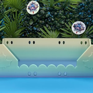 May include: A rectangular plastic shelf with a gradient colour transition from light yellow at the top to light blue at the bottom. The front panel features a scalloped edge, two embossed maple leaf designs, and several small circular ventilation holes.