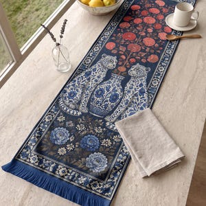 Könnte beinhalten: Ein rechteckiger Tischläufer mit dunkelblauem Hintergrund, der ein zentrales Motiv aus zwei Leoparden neben einer Blumenvase zeigt, umgeben von blauen und roten Blumenmustern, mit blauen Fransen an beiden Enden des Stoffläufers.
