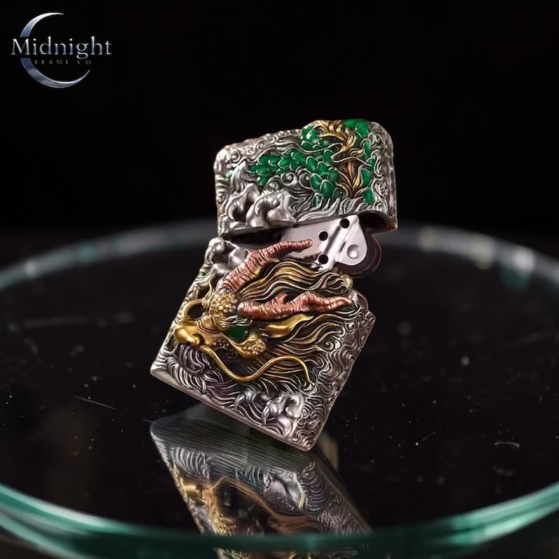 Peut inclure: Briquet argent&eacute; avec un motif de dragon d&eacute;taill&eacute; dans des tons or et cuivre. Le dessus du briquet pr&eacute;sente un motif d'arbre en &eacute;mail vert. La marque "Midnight" est affich&eacute;e dans un logo de croissant de lune.