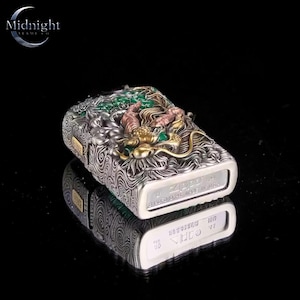 Peut inclure: Un briquet Zippo argent&eacute; avec un motif de dragon orn&eacute; en or, vert et rose. Le briquet pr&eacute;sente un motif tourbillonnant textur&eacute; sur les c&ocirc;t&eacute;s et le logo Zippo est visible. Le briquet se refl&egrave;te sur une surface noire.