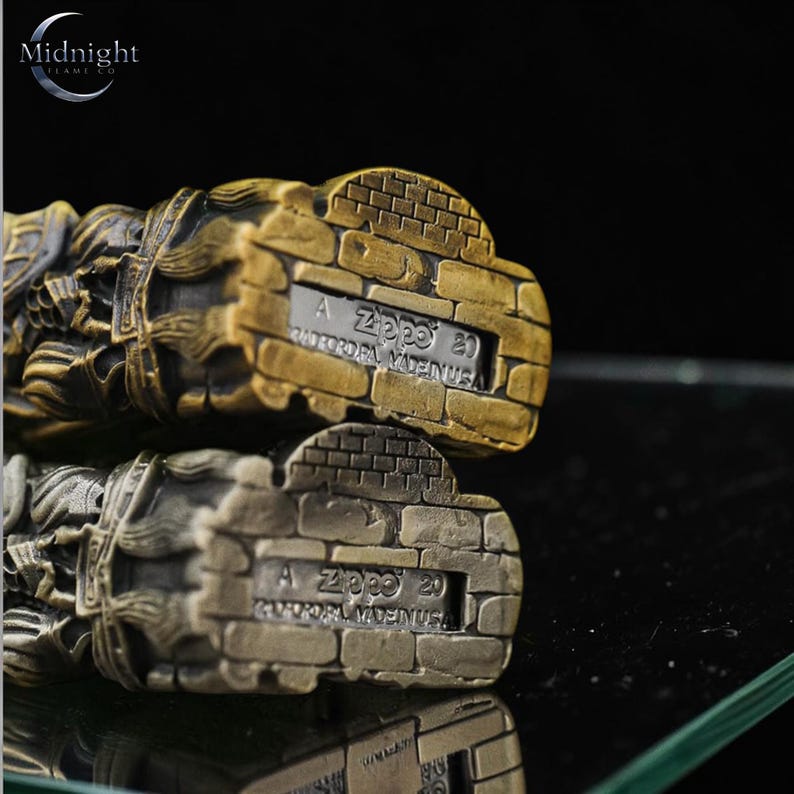 K&ouml;nnte beinhalten: Zwei Zippo-Feuerzeuge mit Backstein-Design. Eines ist bronzefarben, das andere silberfarben. Auf der Unterseite der Feuerzeuge ist der Text "A Zippo 20 BRADFORD, PA. MADE IN USA" eingraviert. Das Logo von Midnight Flame Co. ist sichtbar.