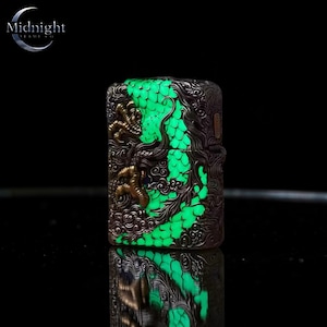 Peut inclure: Un briquet de couleur bronze avec un motif de dragon d&eacute;taill&eacute;. Les &eacute;cailles du dragon brillent en vert vif, contrastant avec le m&eacute;tal plus sombre. Le briquet est de forme rectangulaire et porte le texte "Midnight" en haut &agrave; gauche.