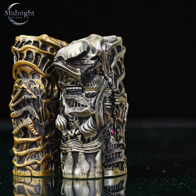 K&ouml;nnte beinhalten: Zwei aufwendig geschnitzte Metallboxen, eine goldene und eine silberne, mit detaillierten Reliefdesigns. Die Boxen weisen verzierte Muster und einen kleinen, roten Edelstein auf. Das Logo von Midnight Trade Co. ist oben links sichtbar.