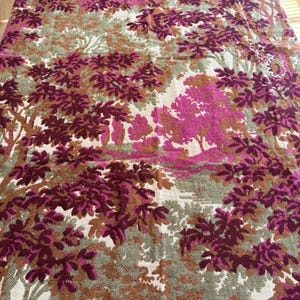 May include: A large textile featuring a forest scene in shades of pink, brown, and green. The design includes stylized trees and foliage, creating a patterned, decorative fabric. The overall aesthetic is vintage and nature-inspired.