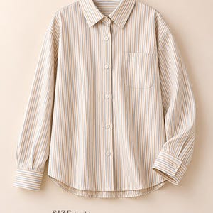 Puede incluir: Una camisa de manga larga con botones y un patr&oacute;n de rayas verticales en color canela, azul y blanco. Cuenta con cuello, un bolsillo en el pecho y pu&ntilde;os abotonados. El texto indica una longitud total de 28 pulgadas, un busto de 27 pulgadas y una longitud de manga de 23 pulgadas.