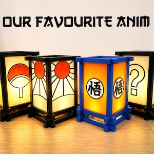 May include: Four illuminated anime-themed lanterns with black frames and various designs. One lantern has a blue frame and orange panels with Japanese characters. The text "OUR FAVOURITE ANIM" is above the lanterns.