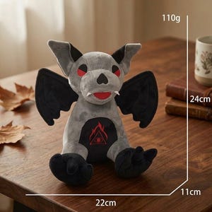 May include: A plush toy bat with gray fur, black wings, and red eyes. The bat has a black belly with a red flame design. It measures approximately 8.7 inches tall, 4.3 inches wide, and 8.7 inches long, and weighs 3.9 ounces.