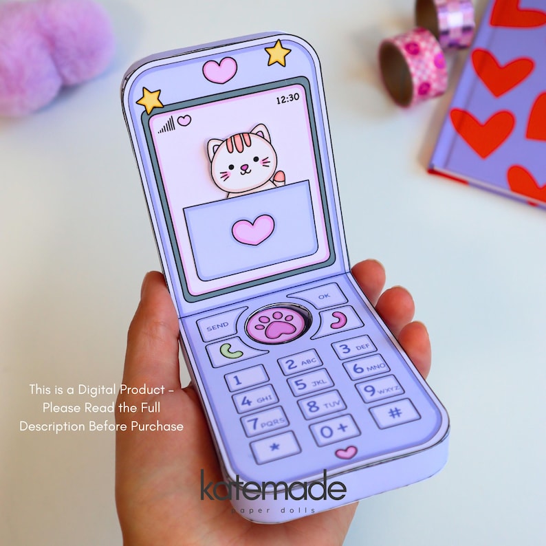 May include: A light purple paper craft flip phone featuring a screen with a cartoon cat illustration, a heart icon, and the time 12:30. The keypad includes numbers, symbols, and a central paw print button. Text on the image reads: This is a Digital Product - Please Read the Full Description Before Purchase.