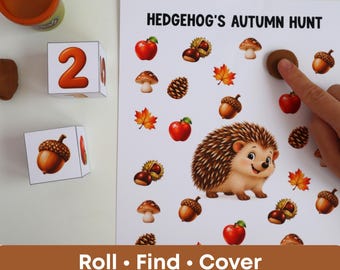 Puede incluir: Una hoja de actividades Hedgehog's Autumn Hunt con una ilustración central de un erizo rodeada de manzanas, setas, bellotas y hojas. Incluye dos dados blancos con números y gráficos de naturaleza, y un recipiente de plastilina marrón.
