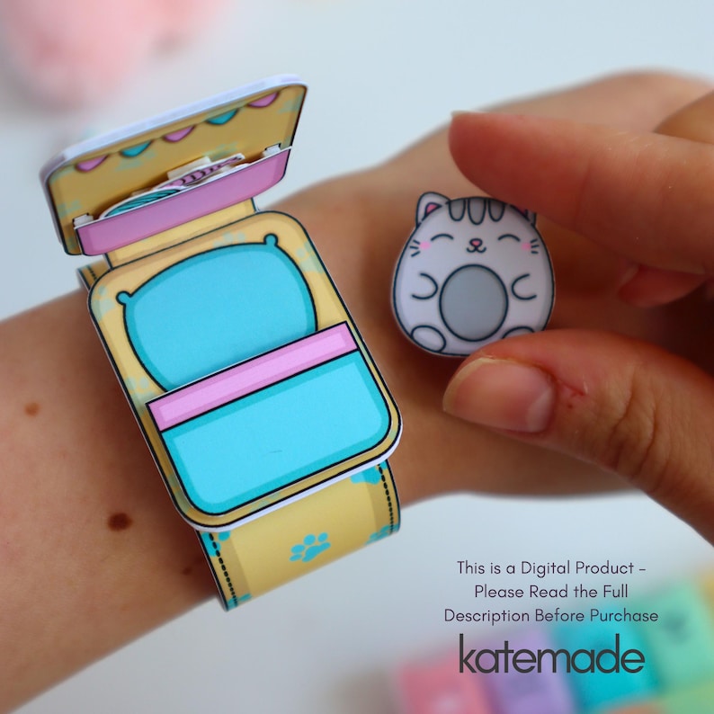 May include: A paper craft bracelet and a cat-shaped charm. The bracelet is yellow with blue paw prints and a bed design. The charm is a white cat with a gray belly. The text "This is a Digital Product - Please Read the Full Description Before Purchase katemade" is visible.
