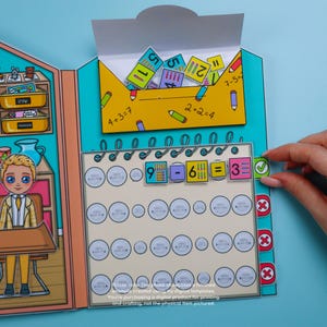 May include: A colorful paper math learning toy with a classroom theme. The toy features a subtraction problem with the answer 3. The image includes the text "4+3=7" and "2+2=4".