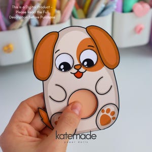 May include: A cartoon dog paper doll with a white body, brown ears, and a brown spot around one eye. The dog has a round, peach-colored belly and paw prints. The text "katemade paper dolls" is at the bottom. The text "This is a Digital Product - Please Read the Full Description Before Purchase" is at the top.