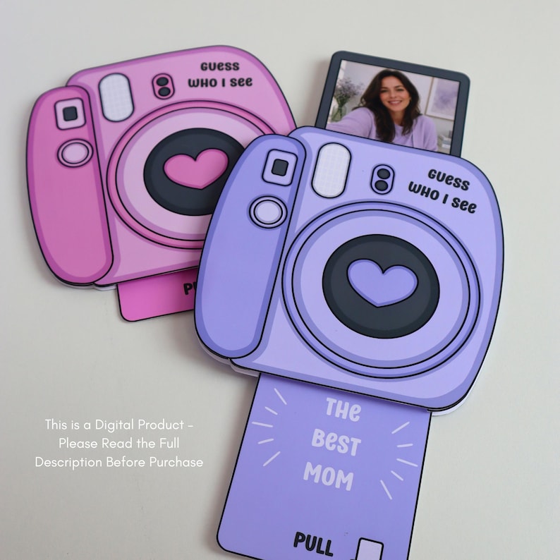 May include: Two decorative camera-shaped cards in shades of pink and purple. The cards have a heart-shaped lens and the text "guess WHO I see". One card has a photo of a person. The bottom of the purple card reads "THE BEST MOM" and "PULL".