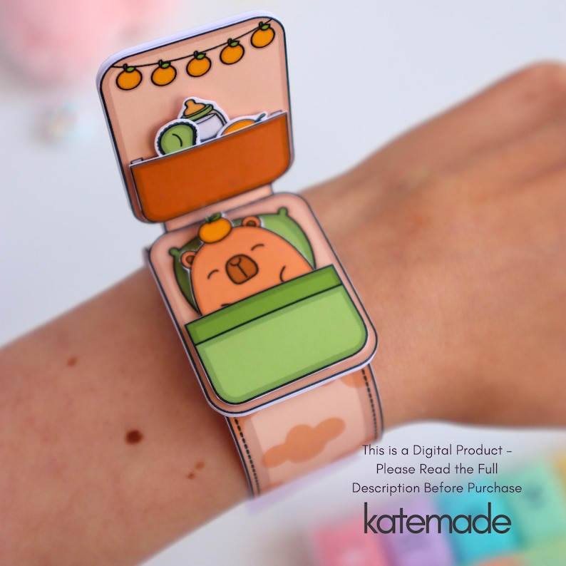 May include: A paper craft wristband featuring a sleeping bear design. The wristband is peach-colored with a repeating cloud pattern. The bear is in a green bed, and the top section has a bottle and fruit. Text on the wristband reads "This is a Digital Product - Please Read the Full Description Before Purchase katemade."