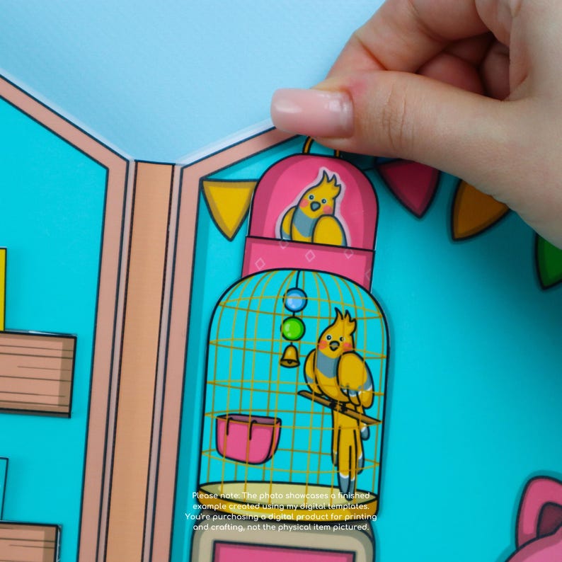 May include: A paper craft featuring a yellow bird in a pink and teal birdcage. The birdcage has a teal base and a pink top. The image includes text that reads, "Please note. The photo showcases a finished example created using my digital templates."