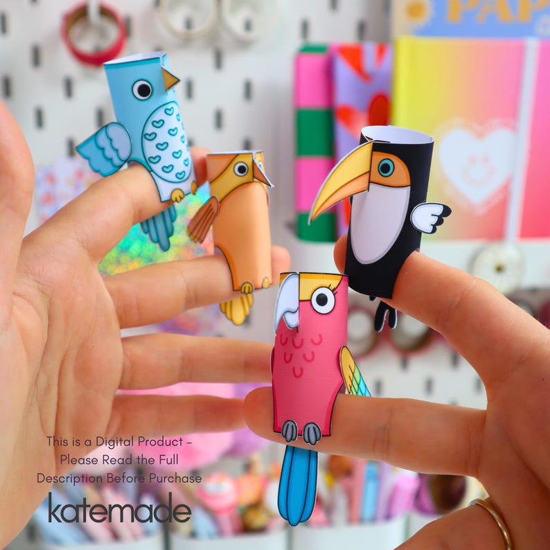 May include: Four paper finger puppets shaped like birds, including a blue bird with white patterns, an orange bird, a black toucan with a yellow beak, and a pink parrot with a white face. The text reads: This is a Digital Product - Please Read the Full Description Before Purchase katemade.