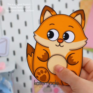 May include: A cartoon fox sticker with orange and brown coloring, large eyes, and a paw print. The sticker is held by a hand. Text on the sticker reads "katemade paper dolls" and "This is a Digital Product - Please Read the Full Description Before Purchase."