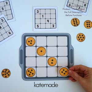 Op de afbeelding: Een printbaar educatief spel met een grijs bakplaat-raster, ronde koekjesfiches met chocoladestukjes en nummerkaarten. De tekst luidt: This is a Digital Product - Please Read the Full Description Before Purchase en katemade.