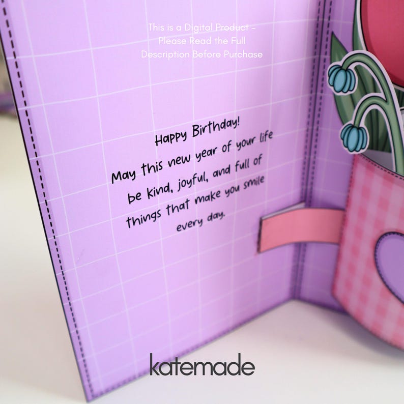 May include: A pop-up birthday card with a lilac grid pattern background. The card features the text "Happy Birthday!" and a message wishing a joyful year. A pink gingham-patterned pot with a heart shape and flowers is visible.
