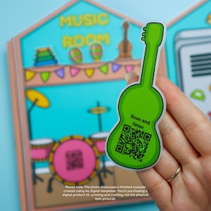 May include: A bright green guitar-shaped sticker with the text "Scan and listen" and a QR code. The sticker is held in front of a colorful illustration of a music room with musical instruments. The background includes the words "MUSIC ROOM".
