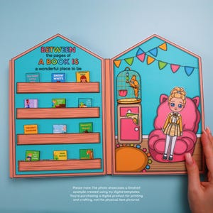 May include: A paper dollhouse with a bookshelf and a room with a doll and a parrot. The bookshelf has miniature books with titles like "Snow White" and "The Ugly Duckling." The room has a pink chair and a parrot in a cage. Text reads "Between the pages of a book is a wonderful place to be."