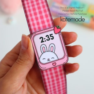 May include: A pink paper watch with a gingham strap and a digital screen displaying the time 2:35. The screen features a cartoon bunny and a strawberry charm. The text "katemade" is visible.