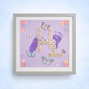 May include: Framed artwork with a lavender background featuring purple footprints, butterflies, and the name "CIARA ROBIN" spelled out with letter tiles. Decorative flowers surround the image.