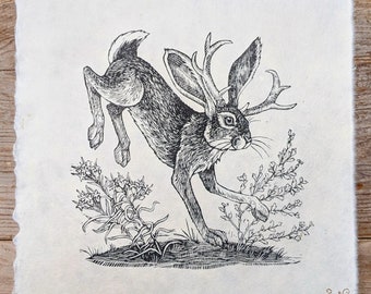 May include: A black and white illustration of a jackalope, a mythical rabbit with antlers, leaping into the air. The jackalope is surrounded by small plants and flowers. The image is titled "Jumping Jackalope" and numbered "23/100".