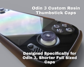 May include: A handheld gaming console featuring Odin 3 Custom Resin Thumbstick Caps. The device has a black front panel, a white thumbstick base, and a textured purple resin cap. Text on the image reads: Odin 3 Custom Resin Thumbstick Caps.