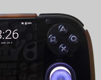 May include: A black mobile gaming controller attachment featuring a standard four-button layout with triangle, circle, cross, and square symbols. The device includes a glowing purple analogue stick and a digital display showing 8:26, 54% battery.