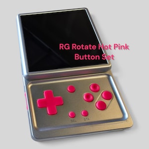 May include: A silver handheld gaming console featuring a black screen and a set of hot pink buttons. The buttons include a directional pad, four action buttons, and two smaller buttons labeled SEL and STA. The text RG Rotate Hot Pink Button Set is visible on the screen.