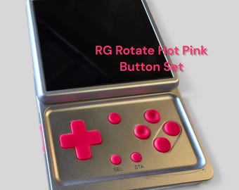May include: A silver handheld gaming console featuring a black screen and a set of hot pink buttons. The buttons include a directional pad, four action buttons, and two smaller buttons labeled SEL and STA. The text RG Rotate Hot Pink Button Set is visible on the screen.