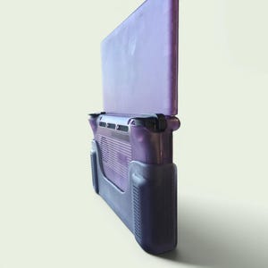 Puede incluir: Una consola de juegos port&aacute;til con una carcasa de pl&aacute;stico p&uacute;rpura transl&uacute;cido. El dispositivo tiene una orientaci&oacute;n vertical con una pantalla en la mitad superior y una secci&oacute;n de agarre en la mitad inferior, incluyendo rejillas de ventilaci&oacute;n.