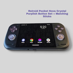 May include: A black handheld gaming console with a screen displaying a digital clock at 5:20 and app icons. It features translucent purplish buttons and matching analog sticks. Text above reads: Retroid Pocket Nova Crystal Purplish Button Set + Matching Sticks.