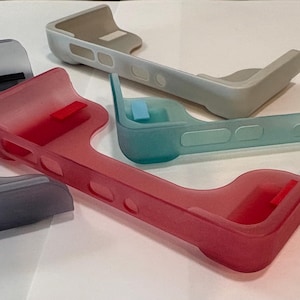 May include: An assortment of translucent plastic phone cases in various colors. The cases are in shades of gray, red, and teal. Each case has a unique shape with rounded edges and cutouts.
