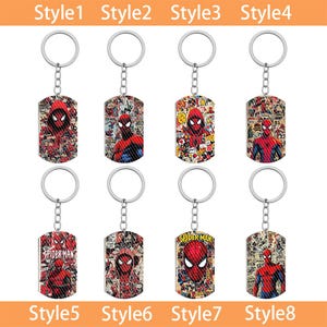 May include: Eight rectangular metal keychains with silver split rings and chains. Each keychain features a unique graphic print of the character Spider-Man in red and blue, with some designs incorporating comic book panels and the text Spider-Man.