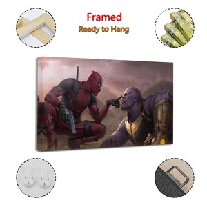 May include: Framed canvas art featuring Deadpool and Thanos in a dramatic pose. Deadpool, in a red and black suit, points at Thanos's nose. Thanos, in purple, wears gold armor. The text "Framed Ready to Hang" is at the top.